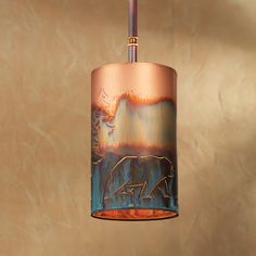 a copper and blue lamp hanging from a ceiling in a room with a wall behind it