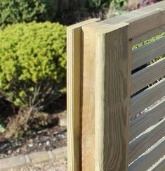 a close up of a wooden slatted fence with plants in the back ground