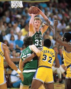 a group of men playing basketball against each other in front of a crowd with people watching