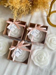 four small boxes with ribbons tied around them on top of a table next to flowers