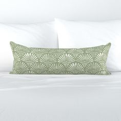 a white bed topped with two pillows and a green pillow case on top of it