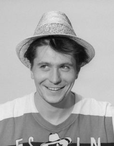 a black and white photo of a man with a hat on smiling at the camera