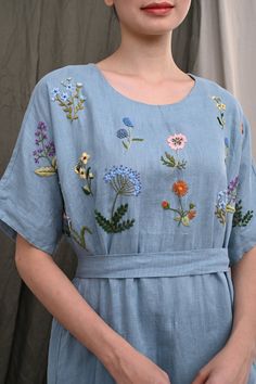 a woman wearing a blue dress with flowers on it