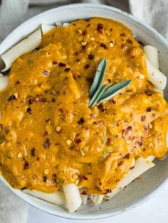 a white bowl filled with pasta and sauce on top of a table next to a napkin