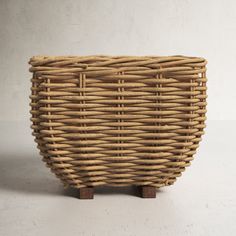 a wicker basket sitting on top of a wooden stand in front of a white wall