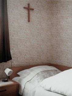 a bedroom with a cross on the wall and a white bed in front of it