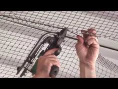 a man holding a pair of scissors in front of a wire mesh fence with wires attached to it