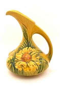 a yellow and green vase with flowers painted on it