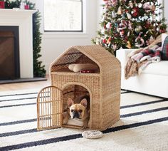 a dog in a pet house on the floor next to a christmas tree and fireplace