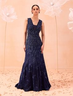 a woman standing in front of flowers wearing a dress with sequins on it