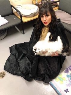 a woman sitting on the floor holding a white dog