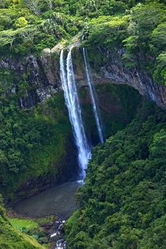 a large waterfall in the middle of a lush green forest