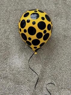 a yellow and black ball sitting on top of a gray carpet next to a string