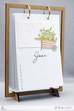 a notepad with a drawing of a wheelbarrow and flowers on it that says june