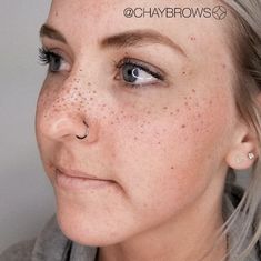 a woman with freckles on her face looking at the camera while wearing a gray sweater