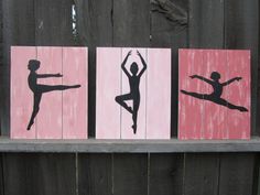 three wooden signs with silhouettes of dancers on them, one is pink and the other is black