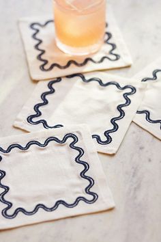 three coasters with black and white designs on them, one has a drink in it