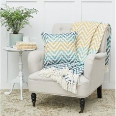 a chair with a blanket on it next to a small table and potted plant