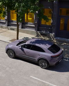 a grey porsche cayen is parked on the side of the road in front of a building