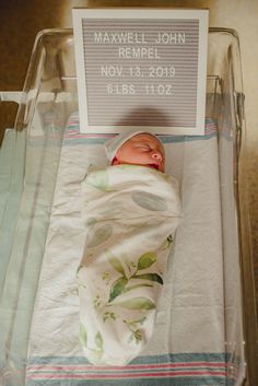 a newborn baby wrapped in a blanket with a sign on the side that reads maxwell john rempel november 13, 2011