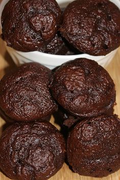 several chocolate muffins in small white bowls on a wooden table