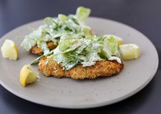 two fried chicken patties with lettuce and lemon wedges on a plate