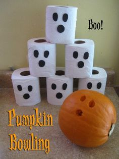 a pumpkin sitting on top of a pile of toilet paper next to some dices