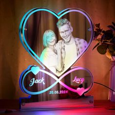 a heart shaped photo frame with the words jack and luv on it next to a vase filled with flowers