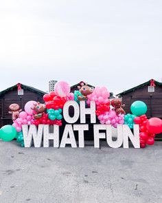 a large sign that says oh what fun surrounded by balloons