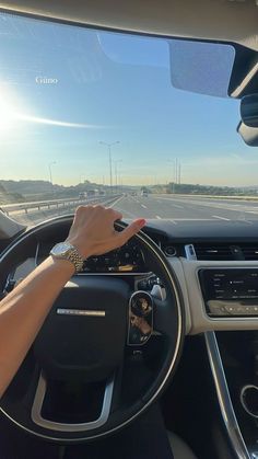 a woman is driving her car on the highway and she has her hand on the steering wheel