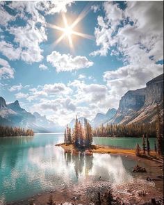 the sun shines brightly over a lake surrounded by mountains and pine trees in the foreground