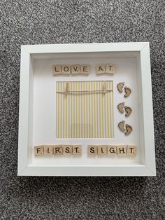 a white frame with some words in it and baby feet on the floor next to them