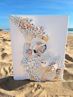 an art piece made out of seashells and shells on the sand at the beach