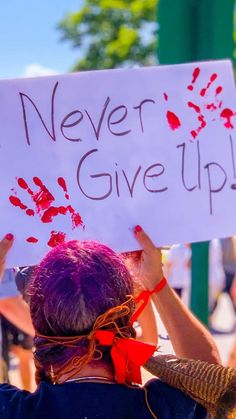 a woman holding a sign that says never give up