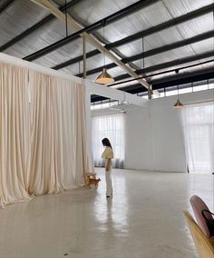 a woman is standing in front of a curtained wall and looking at the floor