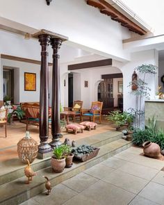 a living room filled with lots of furniture and potted plants on top of stone steps