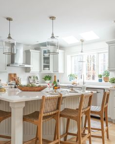 a kitchen with white cabinets and wooden stools in front of an island counter top