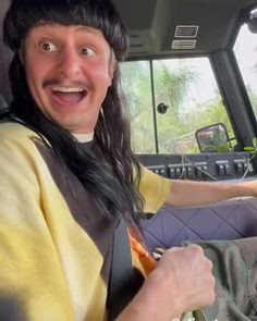 a man with long black hair driving a car