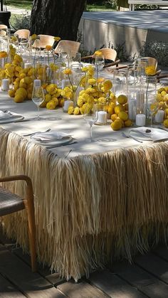 the table is set up with yellow flowers and lemons in vases on it