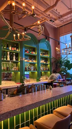 a bar with lots of bottles on the shelves and lights hanging from it's ceiling