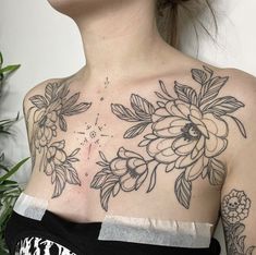 a woman with tattoos on her chest is looking up at the sky and has flowers all over her back