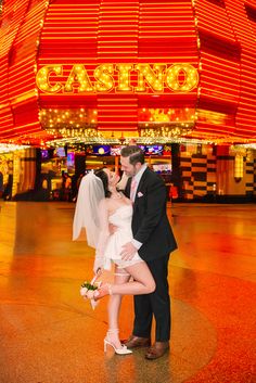 a bride and groom kissing in front of a casino sign