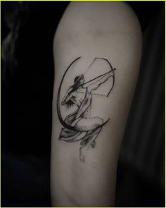 a tattoo on the arm of a woman with an arrow and bow in her hand