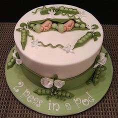 a cake decorated with peas in a pod on top of a green platter that says peas in a pod