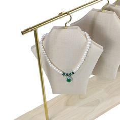 three necklaces are hanging on the clothes rack in front of white linens and gold poles