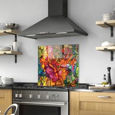 a kitchen with wooden cabinets and stainless steel stove top hood over the range in front of an abstract painting on the wall