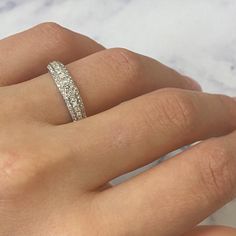 a woman's hand with a diamond ring on her left hand and the other hand holding it