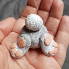 a small teddy bear sitting on top of someone's hand in the palm of their hand