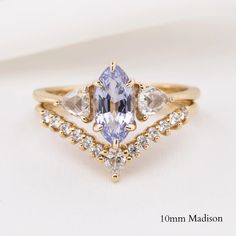 a yellow gold ring with three pear shaped cut diamonds and an aquamarine blue diamond