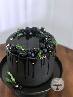 a chocolate cake with blackberries and pine sprinkles on a wooden table